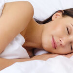 Woman sleeping in bed of white sheets